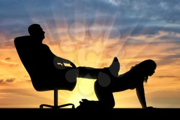 Silhouette of a selfish man with a crown on his head sitting in a chair, threw back his legs on the woman's back. The concept of a businessman is an egoist who does not respect his employees