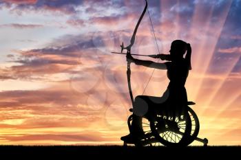 Silhouette of a disabled woman in a wheelchair engaged in sports archery. The concept of disabled people leading an active lifestyle