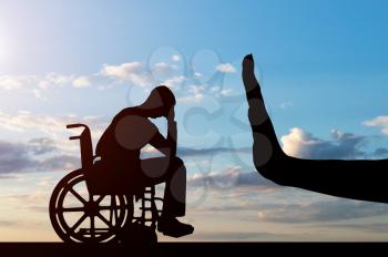 Silhouette of sad disabled man in wheelchair and hand gesture stop. The concept of discrimination and disrespect for people with disabilities