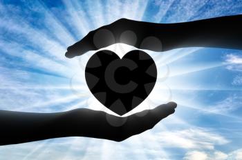 Altruism concept. Silhouette of hands protecting heart symbol
