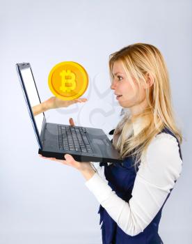 Surprised woman holds a laptop in her hands, hand from a laptop offers bitcoin. The concept of crypto currency