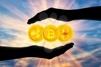 Coins bitcoin, etherium, ripple in the hands of a man under protection. The concept of crypto currency