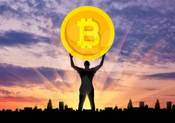 Silhouette of a man holding a coin bitcoin against the background of the city at sunset. The concept of the future for crypto currency