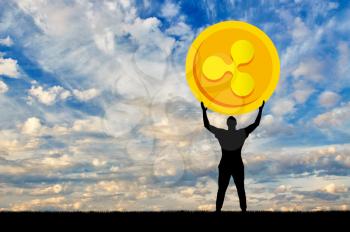 Silhouette of a man holding a ripple coin against the sky. The concept of the future for crypto currency