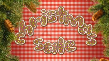 The inscription Christmas sale, consisting of cookies. Against the backdrop of a red tablecloth with fir branches on each side.