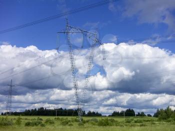 Tower of power lines against white cumulus clouds.