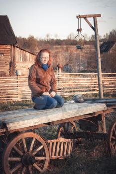 Girl sits on an old cart and dreams. Photo toned.