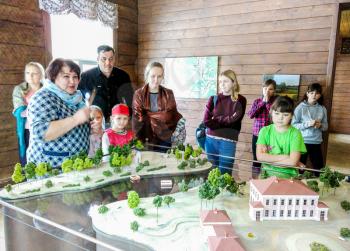 Selo Ovsish, Russia - February 15, 2020: The guide conducts a tour in the museum at the model of the estate. Mobile photo.
