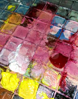 Colorful oil paints on the checkered cells of the palette.
