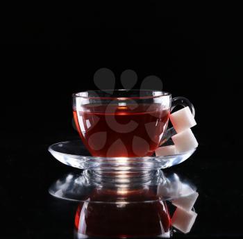 tea in a glass cup on a dark background with sugar