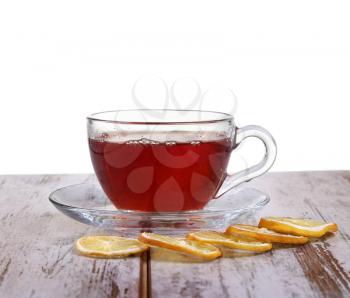 Glass cup with tea and a lemon on a glass saucer isolated on white background