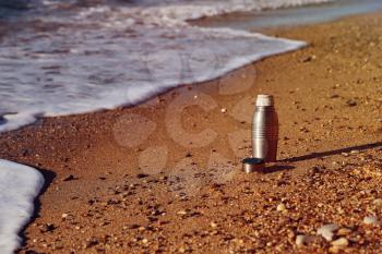 Heat protection-thermos tea cup on the beach,  sandy beach, bank of sea ocean
