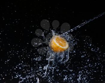 A high-speed shot of a lemon with splashing water, on a black background.