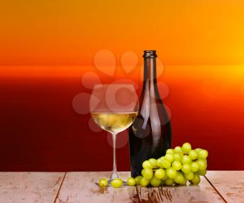 White wine grapes in a glass at sunset on a piece of wood