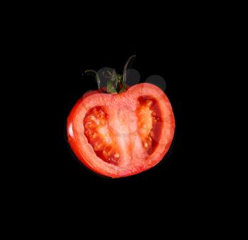 The red tomato cut half-and-half on a black background. Kind with a side.