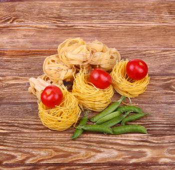 Pasta on the wooden background with tomato, pepper lettuce 