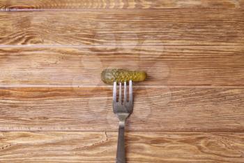 pickled cucumbers on a fork on a wooden board. style rustic. selective focus