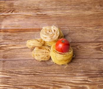 Pasta spaghetti noodles with and tomatoes on wooden table