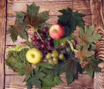 apples, grapes and leaves on wooden
