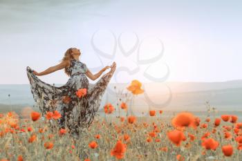 beautiful girl in a poppy field at sunset. concept of freedom