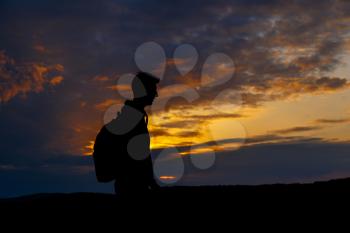 Silhouettes of hiker with backpack enjoying sunset view from top of a mountain. Winner silhouette on the mountain top. Sport and active life concept