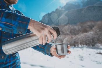 Man holding a thermos in on a snowy mountain