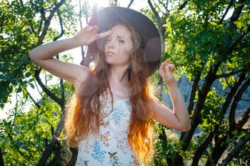 Art work of romantic woman .Pretty tenderness model looking at camera. Red-haired woman with freckles in a hat, on a green juicy background