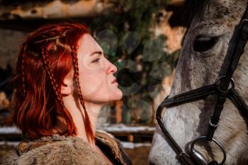 Red-haired woman with a faithful horse preparing for battle