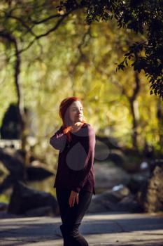 Beautiful red-haired young woman is walking in the autumn park. melancholy mood