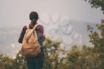 Hipster young girl with backpack enjoying sunset on peak of foggy mountain. Tourist traveler on background view mockup.