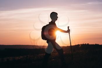Silhouette of a champion on the high mountain. Sport and active life. Silhouette hiker man tracking with backpack and trekking pole,