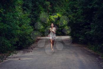 Freedom travel concept. summer weekend. hipster girl wanderlust walking on asphalt road in wild lands. Beautiful young girl with the appearance of southern Asia