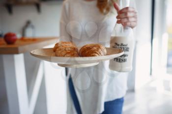 Autumn sseries in the Kitchen, melancholy and warm.. Relaxing in cold weather. red-haired girl holding a tray with pastries and bottle of milk