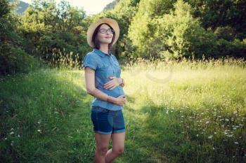 pregnant mom expecting in the summer field. The concept and idea of health, happiness and maternity