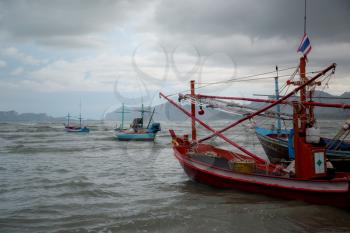 Thai long tail boat during low tide in ocean with carst mountains in background and cloudscape at Thailand, Asia