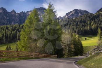 Sunny spring day in Dolomites, picturesque Val di Funes. Rocky peaks and forested mountains surrounded by green Alpine meadows. South Tyrol, North of Italy