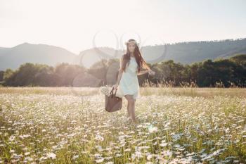 Beautiful girl in daisy field. Summer sunset. happy young lady and spring-green nature, harmony concept. Carefree happy brunette woman with healthy wavy hair having fun outdoor in nature.