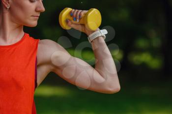 Sporty young woman with dumbbells outdoors. Doing fit activity and training,outside on green grass at park. Fitness, sport and healthy lifestyle