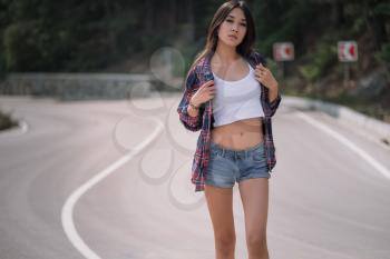Beautiful young woman travels through a mountainous area. The concept and idea of a summer holiday, hitchhiking, finding your own way