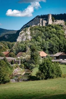 romantic castle on top of a hill in a mountainous valley in the Alps of Switzerland with a blue sky in the background, small village under the rock
