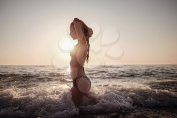 Beautiful emotional Model Girl making splash in the sea and laughing. Beautiful Woman Hot Girl enjoying the Waves of the Ocean. Tropical vacation