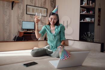 Girl celebrating birthday online in quarantine time through video call virtual party. Coronavirus outbreak 2020. Woman Holding Glass of Wine