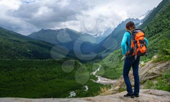 Backpacker on top of a mountain enjoying valley view. wanderlust travel concept, space for text, atmospheric epic moment. Image for trekking, hiking or climbing. North Caucasus, Dombai,, Russia.