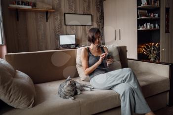 Beautiful young woman with a house cat on the couch. cozy family atmosphere.