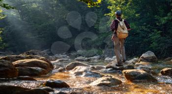 Happy male hiker trekking outdoors in forest near river. idea and concept of adventure, discovery and travel