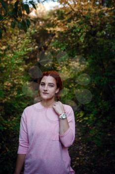 Beautiful young red-haired woman in the autumn forest. idea and concept of free time, happiness, care and freedom, outdoor activities and a healthy lifestyle