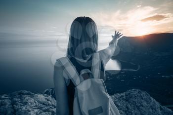 Young woman with a backpack enjoys the view of the mountains and the sea at sunset. Lifestyle emotional concept vacations weekend getaway aerial Crimea landscape