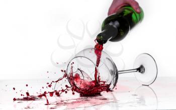 broken wine glass on a quilted table isolated on white background. red wine spills from shards