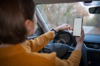 Mockup image of a woman holding and using mobile phone with blank screen while driver a car. People, Driving, Navigation and Transportation Concepts