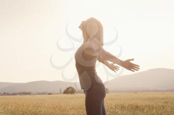 Young girl spreading hands with joy and inspiration facing the sun. She is enjoying serene nature workout vacation outdoors. asian beauty.